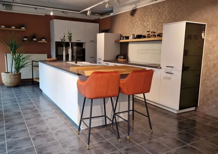 Kücheninsel und Küchenzeile mit beiger Wand und orangenen Thekenstühlen